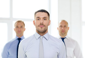 Image showing serious businessman in office with team on back