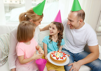 Image showing smiling family with two kids in hats with cake