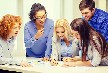 Image showing smiling creative team looking over clothes designs