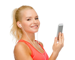 Image showing smiling sporty woman with smartphone and earphones