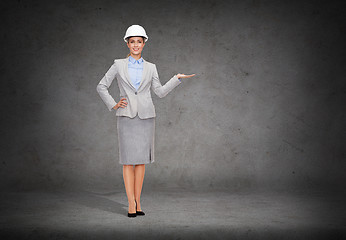 Image showing businesswoman in helmet holding something on palm