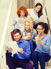 Image showing team with papers and take away coffee on staircase