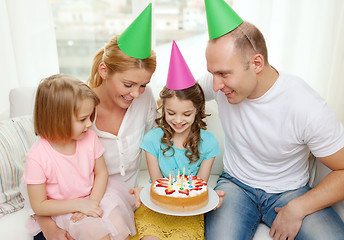 Image showing smiling family with two kids in hats with cake