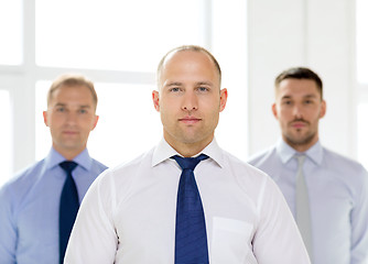 Image showing serious businessman in office with team on back