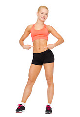 Image showing smiling sporty woman pointing at her six pack