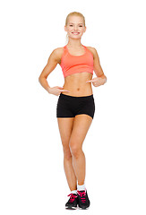 Image showing smiling sporty woman pointing at her six pack