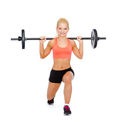 Image showing smiling sporty woman exercising with barbell