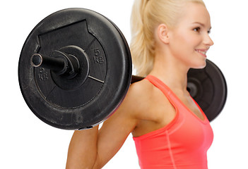 Image showing smiling sporty woman exercising with barbell