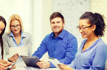 Image showing smiling team with table pc and papers working