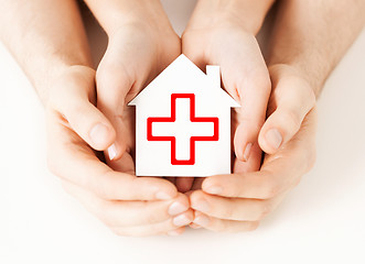 Image showing hands holding paper house with red cross