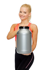 Image showing smiling sporty woman with jar of protein