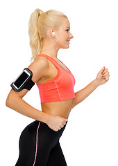 Image showing sporty woman running with smartphone and earphones