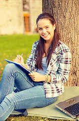 Image showing smiling teenager writing in notebook