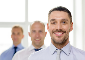 Image showing smiling businessman in office with team on back