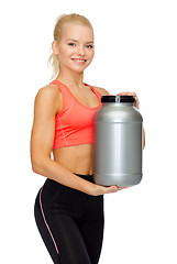 Image showing smiling sporty woman with jar of protein