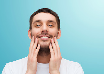 Image showing beautiful smiling man touching his face