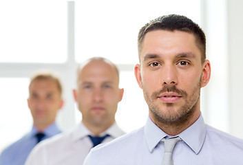 Image showing serious businessman in office with team on back