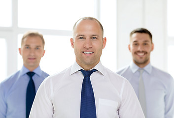 Image showing smiling businessman in office with team on back