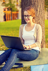 Image showing smiling teenager in eyeglasses with laptop