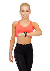 Image showing smiling woman with heart rate monitor on hand