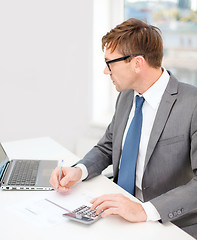 Image showing businessman with computer, papers and calculator