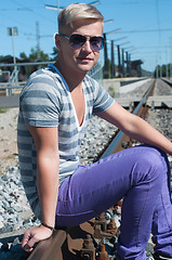 Image showing Young man sitting on the rail track