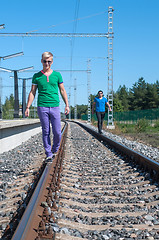 Image showing Two young men walking on the rail track