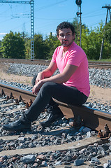 Image showing Young man sitting on the rail track