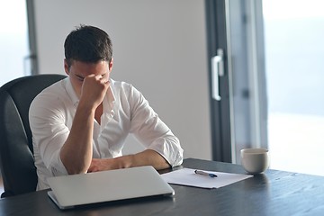 Image showing frustrated young business man working on laptop computer at home