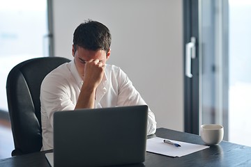 Image showing frustrated young business man working on laptop computer at home