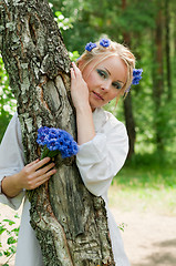 Image showing Beautiful young woman hiding behind the tree