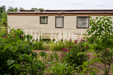 Image showing travel mobile house in garden between the flowers  