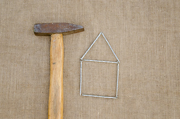 Image showing old hammer and house made ??of nails linen texture 