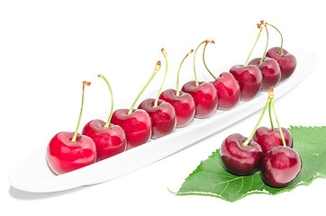 Image showing Big dark red ripe cherry berry row arranged on long white dish