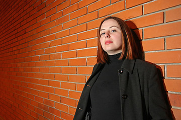 Image showing Young woman in front of brick wall