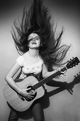 Image showing Young woman wildly playing guitar black and white