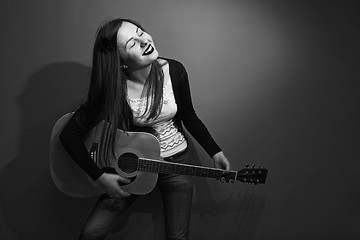 Image showing Brunette enjoys playing guitar black and white