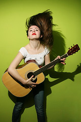 Image showing Young brunette wildly playing guitar