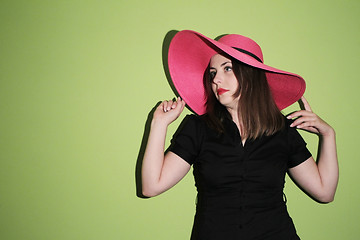 Image showing Girl with pink straw hat on green background