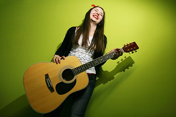 Image showing Young brunette enjoys playing guitar