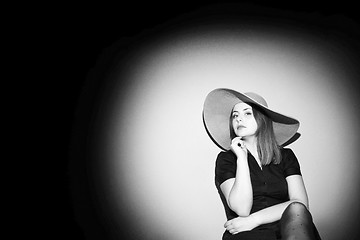 Image showing Young woman with pink hat posing on bed black and white