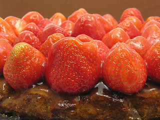 Image showing Lateral close-up view of a strawberry cake on brown background