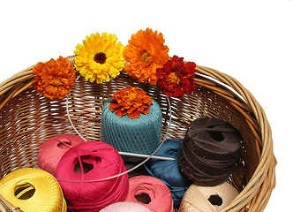 Image showing A basketful of multi-coloured woolen yarn and flowers