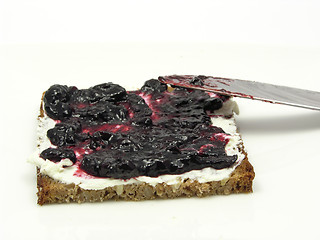 Image showing Wholemeal butterbread  with bilberry jam placed on a round plate with knife