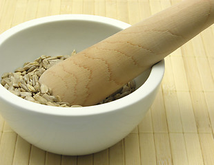 Image showing Pestling sunflower seeds in a bowl of chinaware