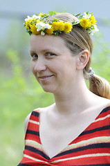 Image showing The happy woman with a wreath from yellow flowers on the head.