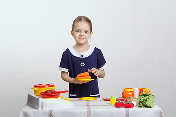 Image showing Girl with a plate of carrots on toy kitchen