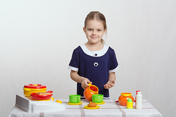 Image showing Girl pours a cup of cream in children's kitchen