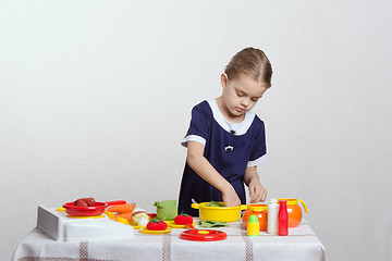 Image showing Girl enthusiastically picks pan in the kitchen