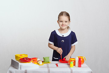 Image showing girl having fun in the kitchen cutting tomato